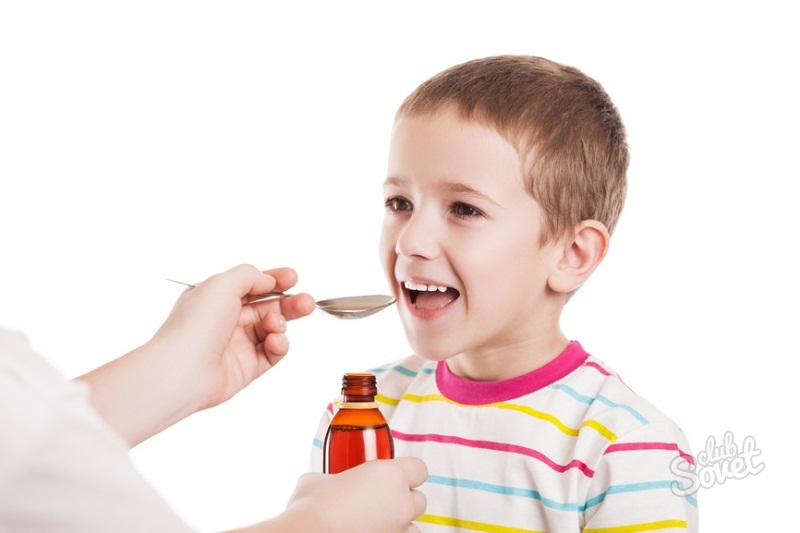 Leende pojke tar medicinsk sirap från en sked i händerna på en läkare eller förälder